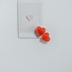 Heart-shaped candies alongside a Polaroid frame on a white background, perfect for romantic occasions.